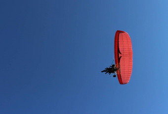 滑翔伞乘客红色的滑翔伞电动机飞行蓝色的天空