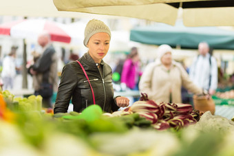 女人购买蔬菜当地的食物市场