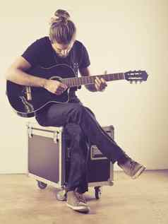 年轻的男人。坐着玩吉他