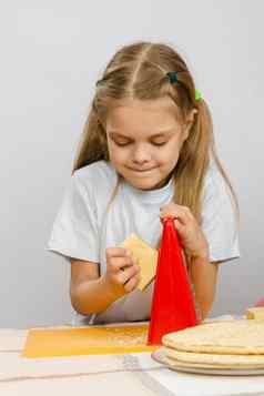 六年女孩摆姿势厨房表格奶酪刨丝器手