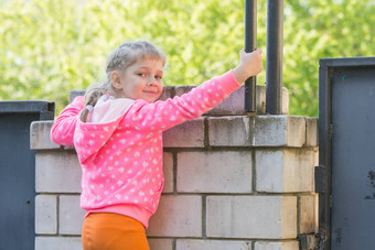 五年女孩爬上砖栅栏转看起来框架