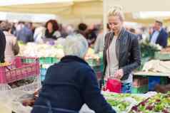 女人购买蔬菜当地的食物市场