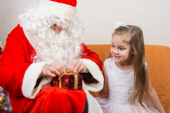 圣诞老人老人帮助解开丝带礼物女孩幸福的