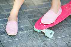女孩站粉红色的滑板在户外