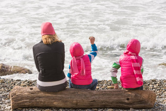 女孩女人坐着日志海滩扔石头水
