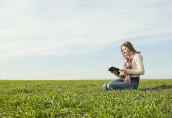 青少年女孩阅读书坐着草