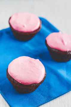 巧克力纸杯蛋糕粉红色的奶油蓝色的餐巾
