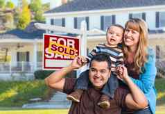 年轻的家庭前面出售真正的房地产标志房子