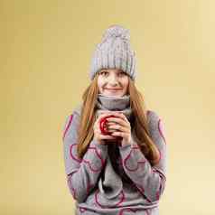 女孩穿灰色的羊毛帽围巾持有红色的杯