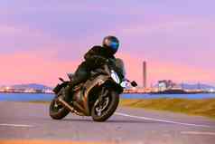 年轻的男人。骑体育运动巡回演出摩托车沥青高速公路