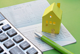 储蓄账户存折计算器笔黄色的纸房子绿色背景