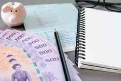 空白笔记本铅笔储蓄账户存折眼睛眼镜泰国钱小猪银行灰色的背景
