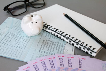 空白笔记本铅笔储蓄账户存折眼睛眼镜泰国钱小猪银行灰色的背景