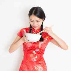 东方女孩红色的旗袍吃筷子