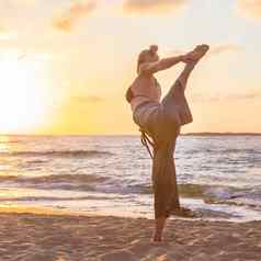 女人练习瑜伽海海滩日落