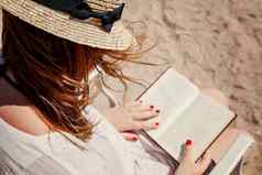 年轻的成人女人他海滩阅读书