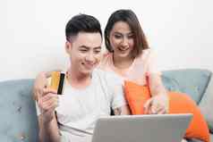 年轻的亚洲夫妇冲浪互联网购物移动PC现代白色公寓背景