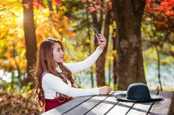 美丽的<strong>女人</strong>秋天森林公园采取自<strong>拍照片</strong>智能手机