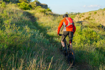骑自行车的人红色的夹克骑山自行车美丽的春天小道旅行冒险体育运动概念