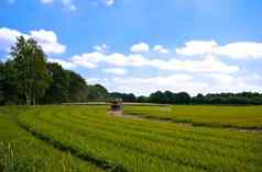 明亮的绿色农业农田拖拉机sprinkle-sweeper安装多云的蓝色的天空