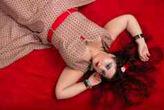 美女照片女孩摆姿势红色的床上