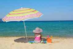 女孩坐着海滩遮阳伞
