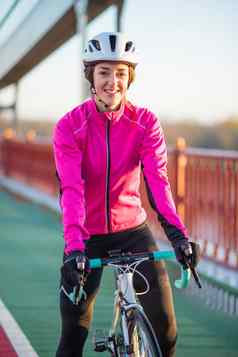 肖像年轻的微笑女骑自行车的人粉红色的夹克休息路自行车冷阳光明媚的秋天一天