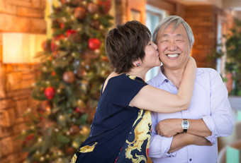 快乐高级中国人夫妇接吻前面装饰圣诞节树