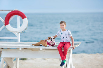 英俊的男孩青少年快乐支出时间朋友斗牛犬海一边孩子狗持有玩海星星关闭生活浮标浮动穿红色的<strong>裤子裤子</strong>拖鞋t恤