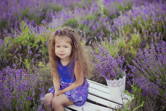 漂亮的年轻的女孩坐着薰衣草场不错的他乘船的人紫色的花