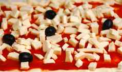 生披萨装饰马苏里拉奶酪黑色的橄榄番茄酱汁