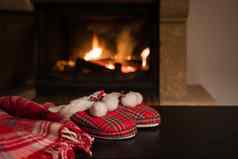 羊毛温暖的毯子格子红色的拖鞋pompons背景燃烧壁炉