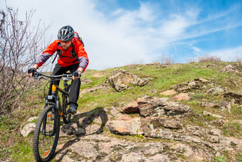 骑自行车的人红色的夹克骑山自行车岩石山极端的体育运动冒险概念