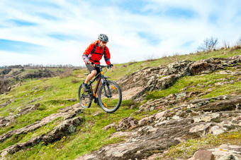 骑自行车的人红色的夹克骑山自行车岩石山极端的体育运动冒险概念