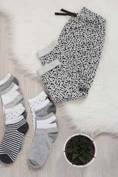 颜色袜子灰色的裤子灰色的木地板上皮毛地毯植物购物概念