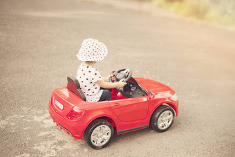 女孩穿着白色黑头衬衫他开车红色的玩具车公园婴儿女孩孩子玩车太阳太阳阴霾眩光