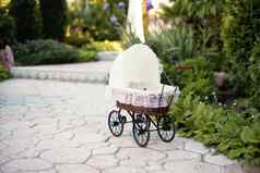 娃娃的婴儿车古董娃娃巡回演出的演员石头人行道小巷美丽的花园花树复古的车娃娃使藤白色花边