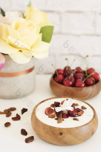 燕麦片酸奶水果樱桃葡萄干椰子芯片在一夜之间早餐健康的食物概念健身情绪饮食夏天光零食明亮的砖墙背景