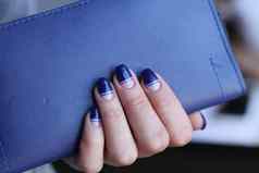 美丽的女手修指甲持有皮革离合器黑暗蓝色的指甲波兰的有创意的设计