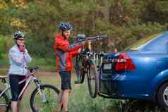 年轻的夫妇被卸载山自行车自行车架车冒险家庭旅行概念