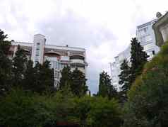 绿色树开花灌木高亮建筑酒店现代公寓建筑背景多云的天空