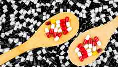 色彩斑斓的抗生素胶囊药片木勺子黑色的白色背景胶囊药物电阻概念抗生素药物合理的全球医疗保健概念制药行业药店背景