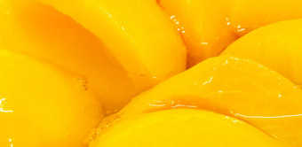 特写镜头罐头桃子半糖浆黄色的水果