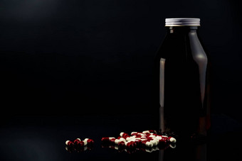 红色的白色抗菌胶囊药片琥珀色的玻璃瓶黑暗背景空白标签复制空间文本抗生素药物电阻药物合理的概念