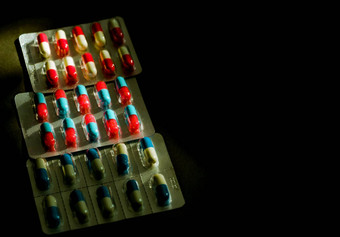 色彩斑斓的抗生素胶囊药片泡包黑暗背景复制空间医学感染疾病抗生素药物合理的药物电阻医疗保健概念