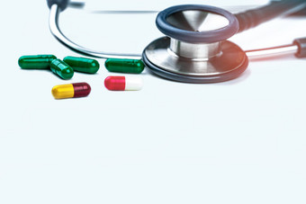 绿色听诊器桩抗生素胶囊药片白色背景抗菌药物电阻过度使用医疗设备医生抗生素药物合理的概念