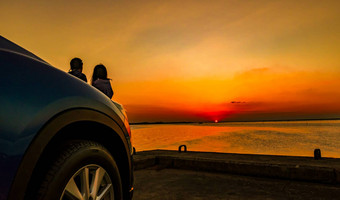 轮廓幸福夫妇站放松海滩前面车橙色蓝色的天空日落夏天假期旅行概念浪漫的年轻的夫妇约会海边
