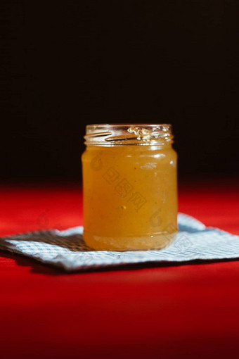 蜂蜜玻璃Jar关闭黑色的背景红色的木表格对于蜂蜜坚持蜂蜜七星