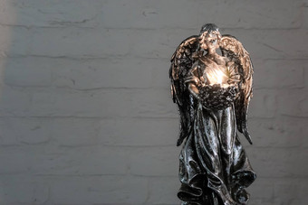 银天使雕像持有燃烧茶光蜡烛传统的圣诞节精神上的背景