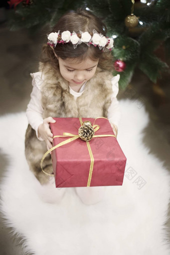 漂亮的女孩孩子持有大圣诞节礼物前面圣诞节树圣诞节概念背景